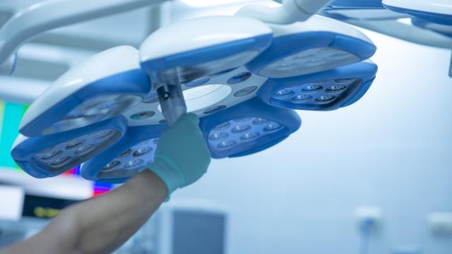 Una enfermera ajusta las luces en un quirófano.