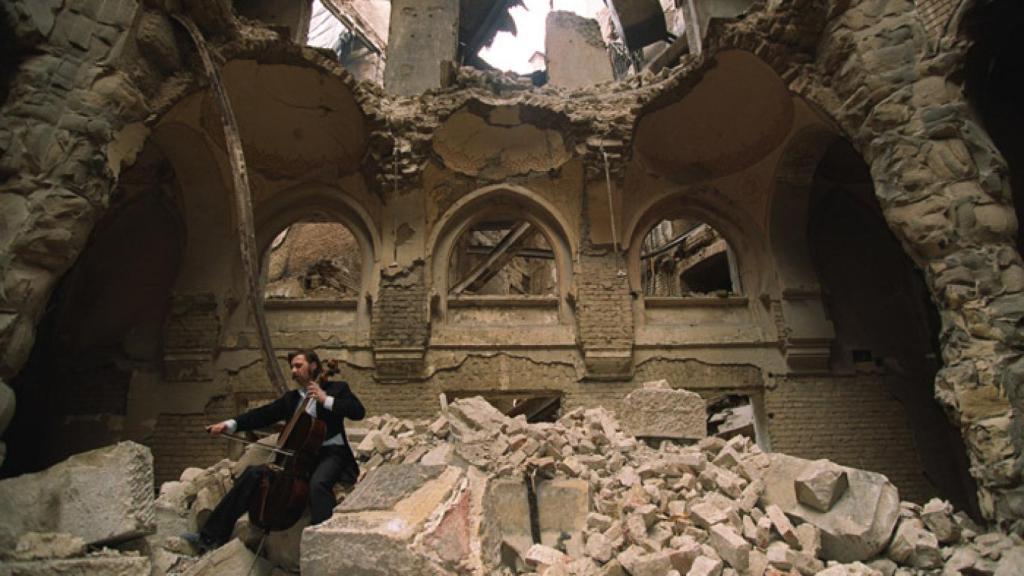 Vedran Smailović tocando en el edificio destruido de la Biblioteca Nacional de Sarajevo en 1992. Foto:  Mikhail Evstafiev