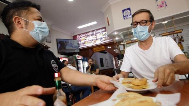 Personas con mascarillas en el interior de un bar.