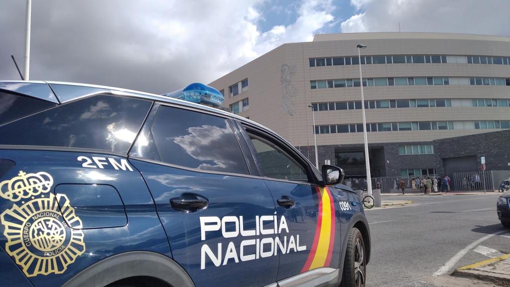 Un coche de la Policía Nacional y, de fondo, los juzgados de Elche.