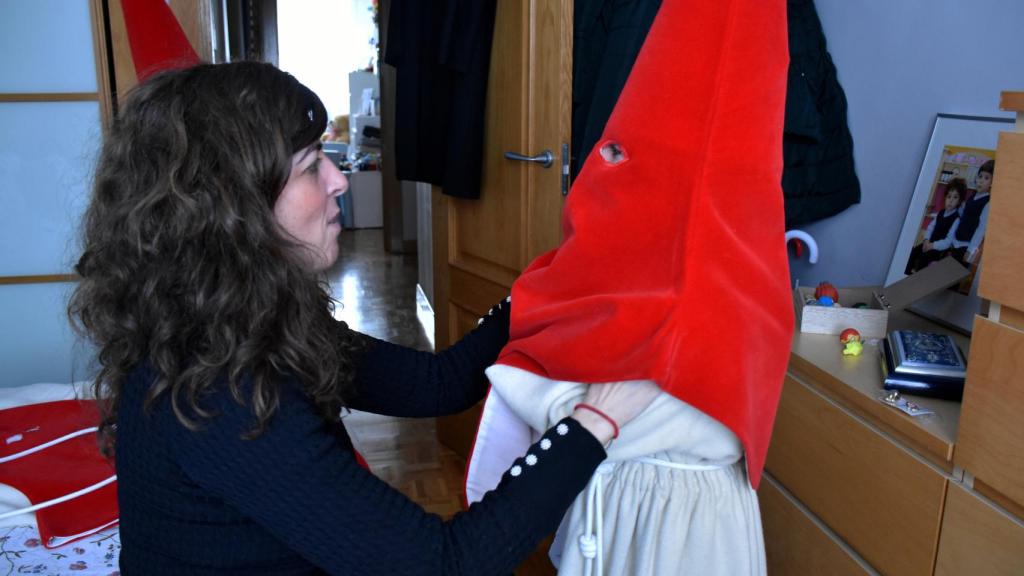 María José ayuda a uno de sus niños a ponerse el caperuzo rojo del Silencio