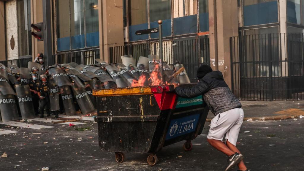 Un manifestante intenta lanzar un contenedor a los agentes. Efe