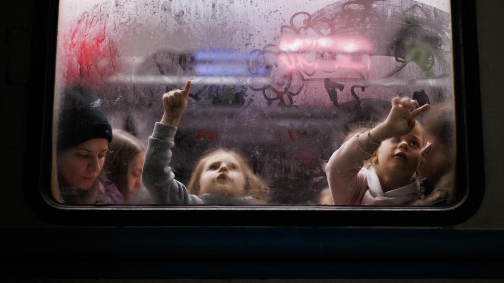 Dos niñas pintan el cristal de uno de los vagones de la estación de tren de Lviv
