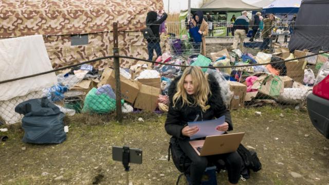 Julia Higueras emitiendo para el Programa de radio de 'Anoche tuve un sueño' desde la frontera (Medyka). Detrás, el corredor por donde llegan los refugiados ucranianos.