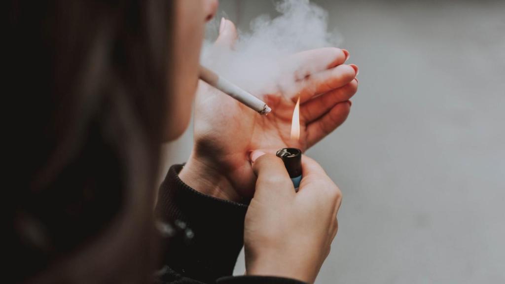 Una persona encendiéndose un cigarro.