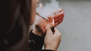 Una persona encendiéndose un cigarro.