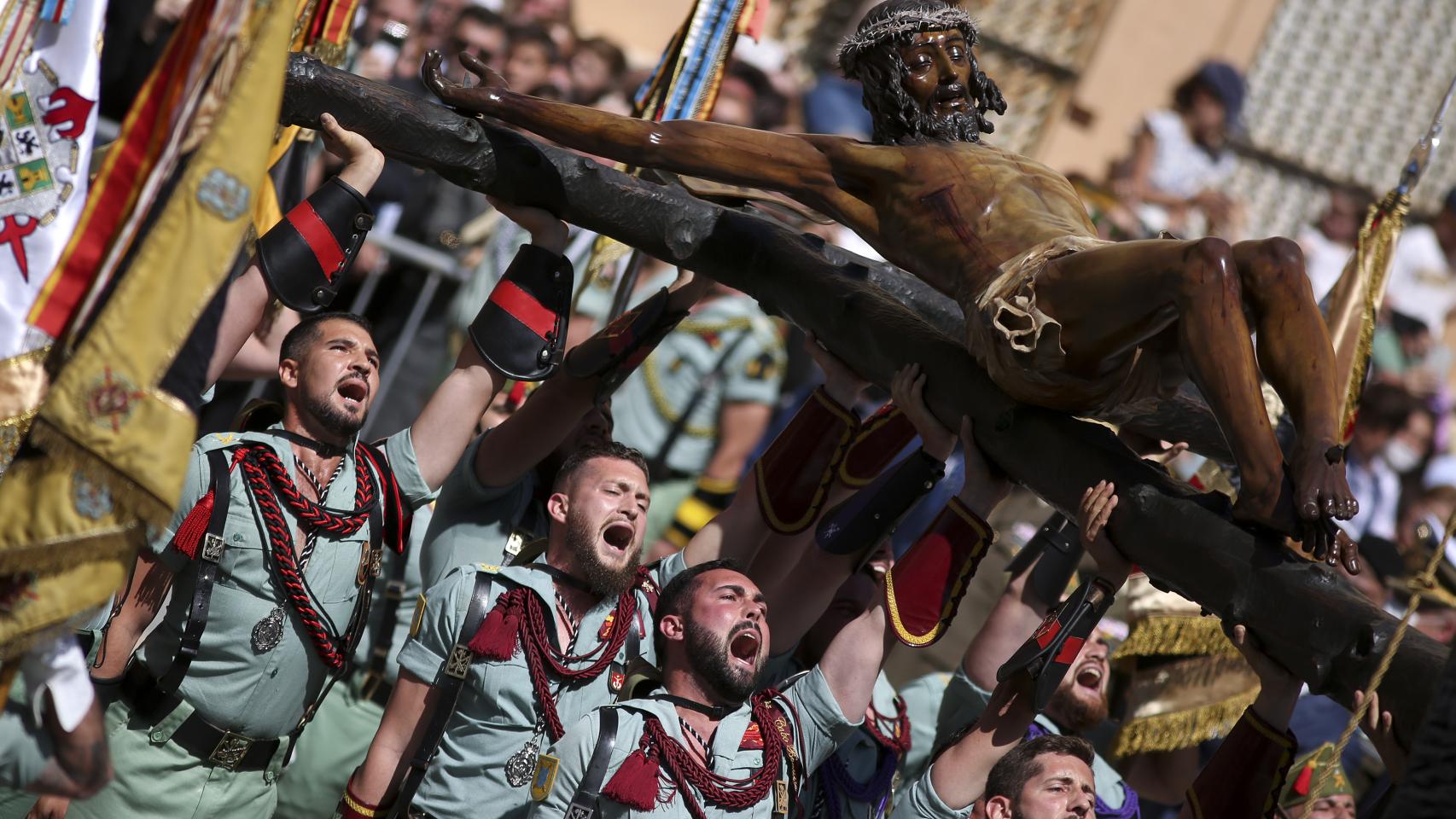 Legionarios del Tercio Gran Capitán, con sede en Melilla, alzan la figura del Cristo de la Buena Muerte y Ánimas mientras lo trasladan a la casa hermandad de la Cofradía de Mena este Jueves Santo en Málaga.