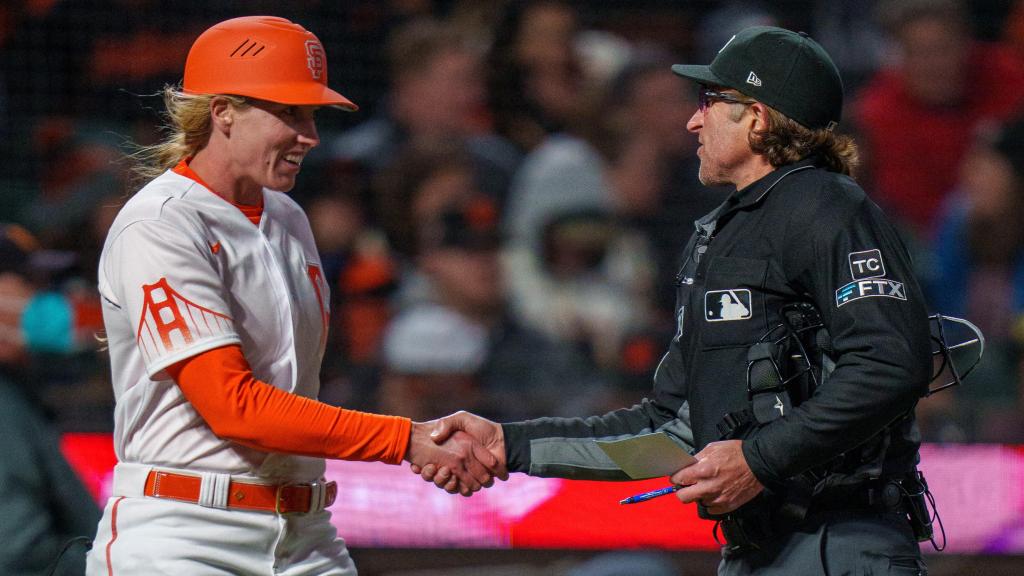Alyssa Nakken felicitada por el árbitro después de dirigir su primer partido oficial en la MLB