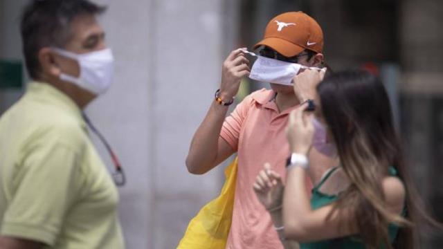 Un joven se pone la mascarilla en la calle.