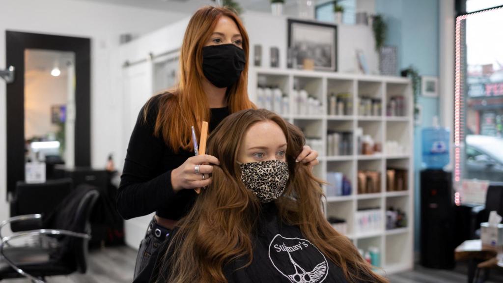 Una peluquera y su clienta, con mascarillas.