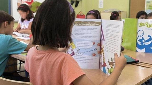 Una niña leyendo en un aula.