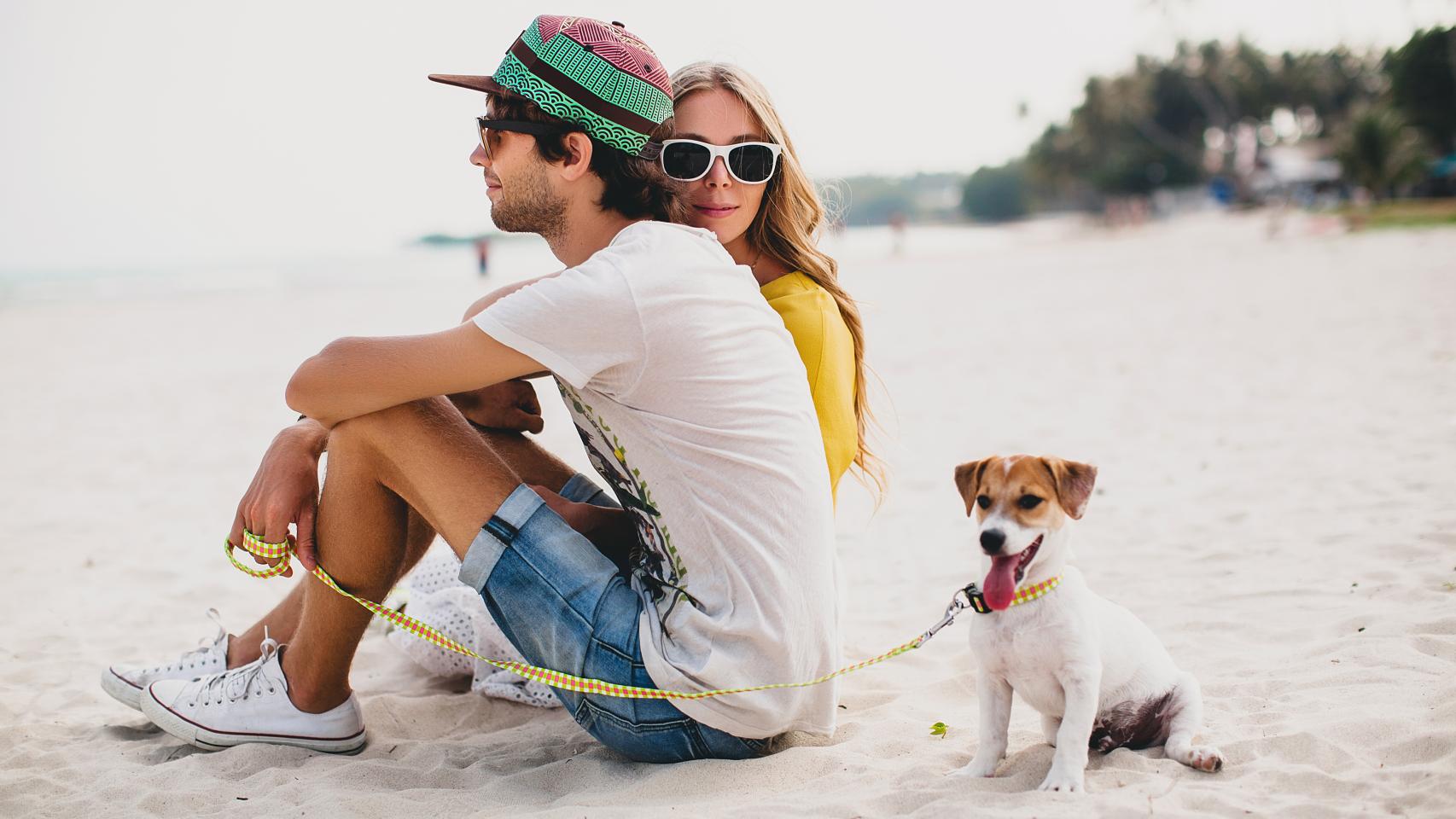 Imagen de archivo de una pareja en la playa con su mascota.