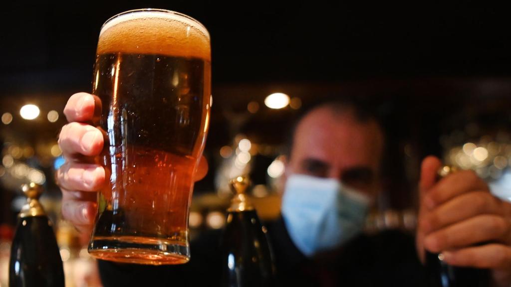 Un camarero sirve una jarra de cerveza.
