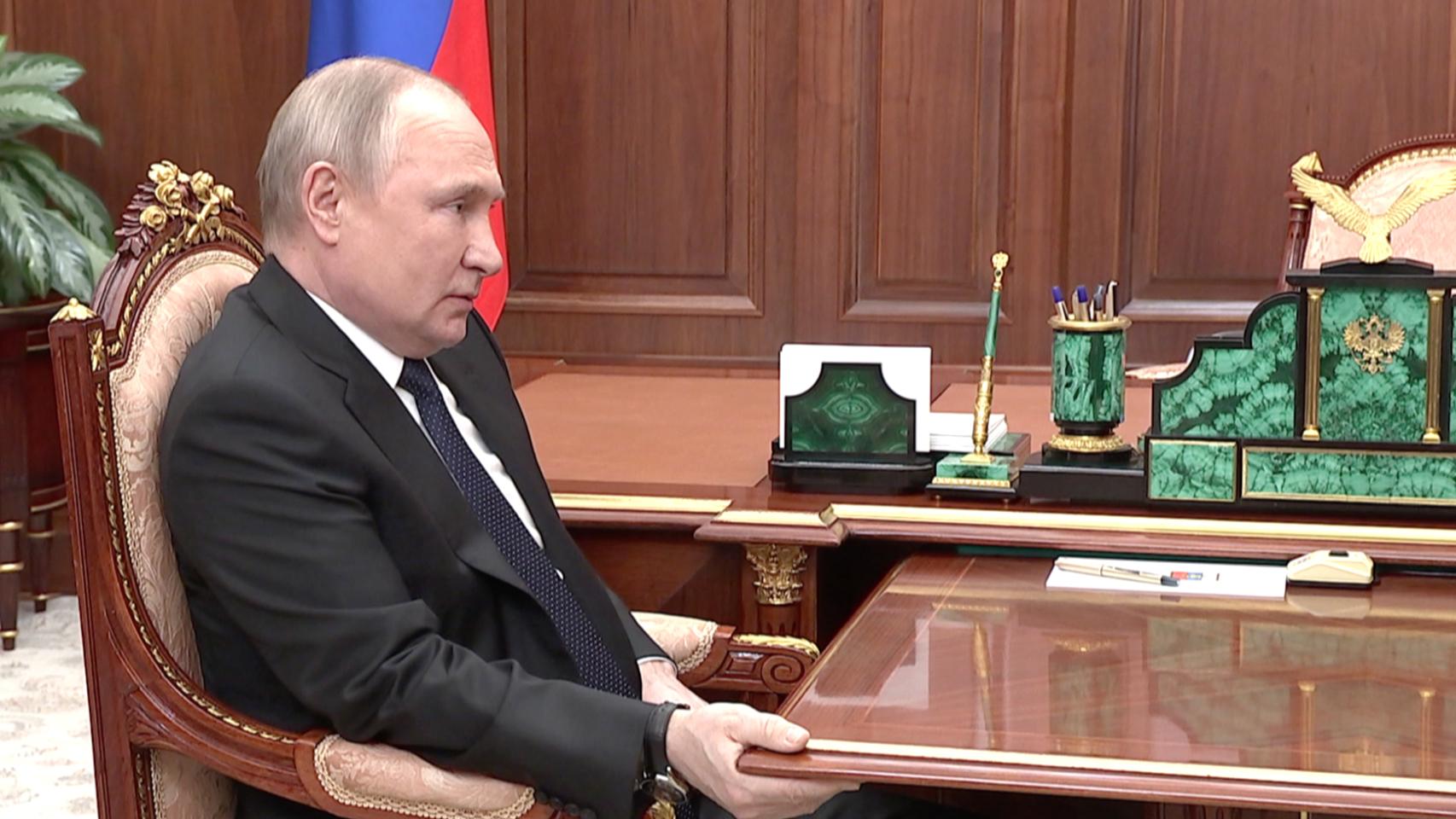 Vladimir Putin, sujetándose a la mesa en una reunión televisada.
