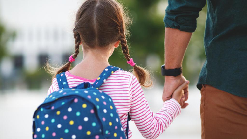 Imagen de archivo de una niña de camino al colegio junto a su padre.