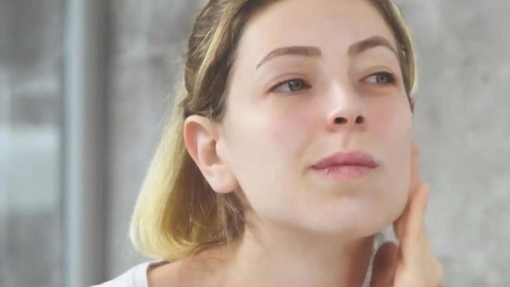 Mujer aplicando producto cosmético en el rostro.