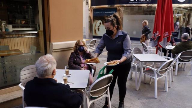 Imagen de archivo de una camarera sirviendo churros a dos clientas, en Málaga.