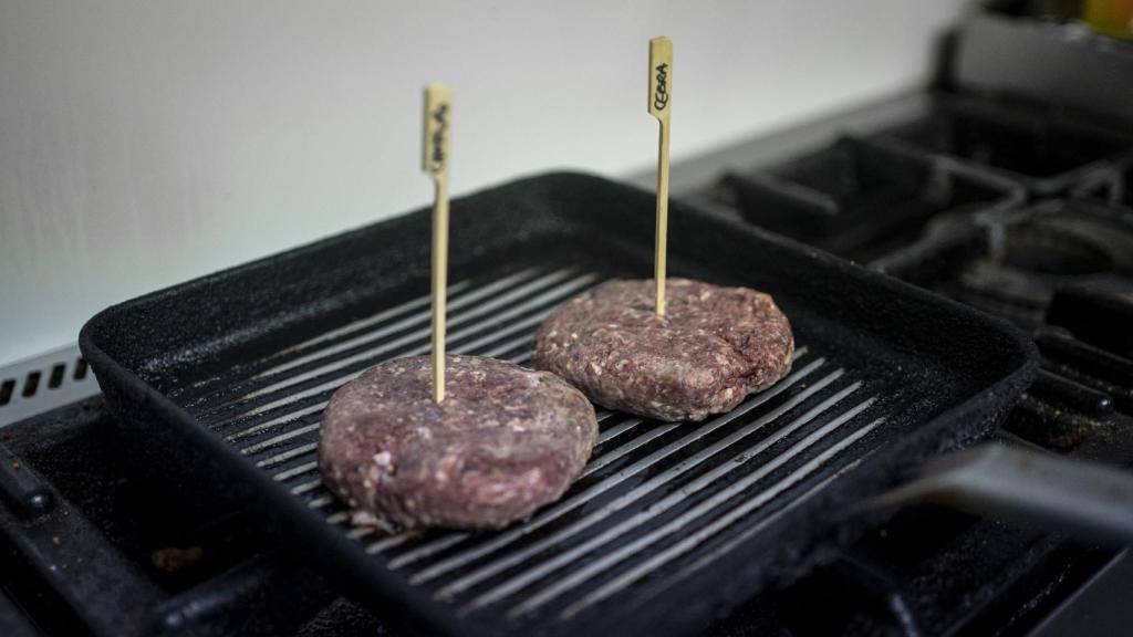 Las hamburguesas de canguro y cebra cocinándose en la plancha.