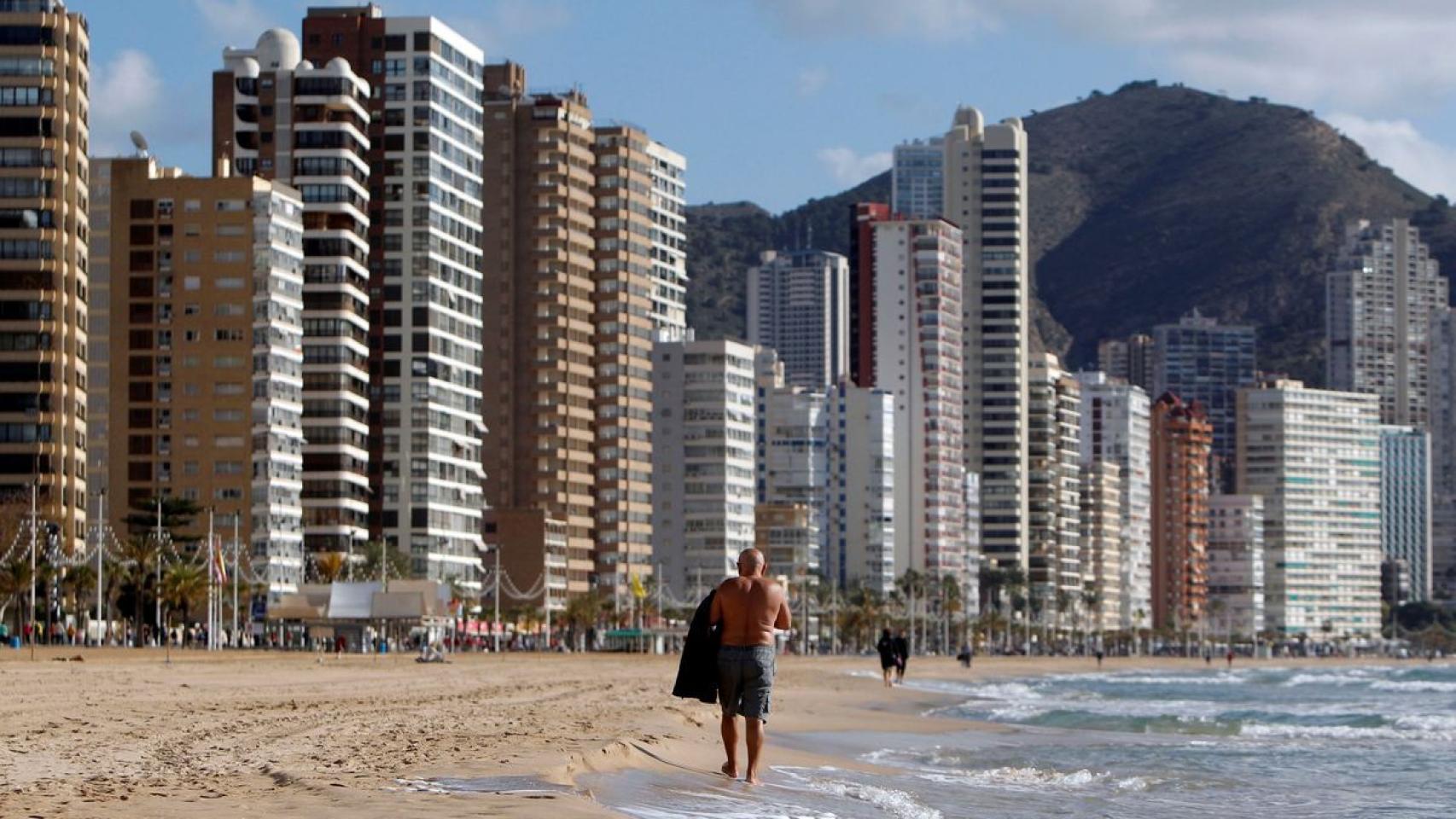 Un turista pasea por la playa de Benidorm, con su 'skyline' al fondo, hace unos meses.