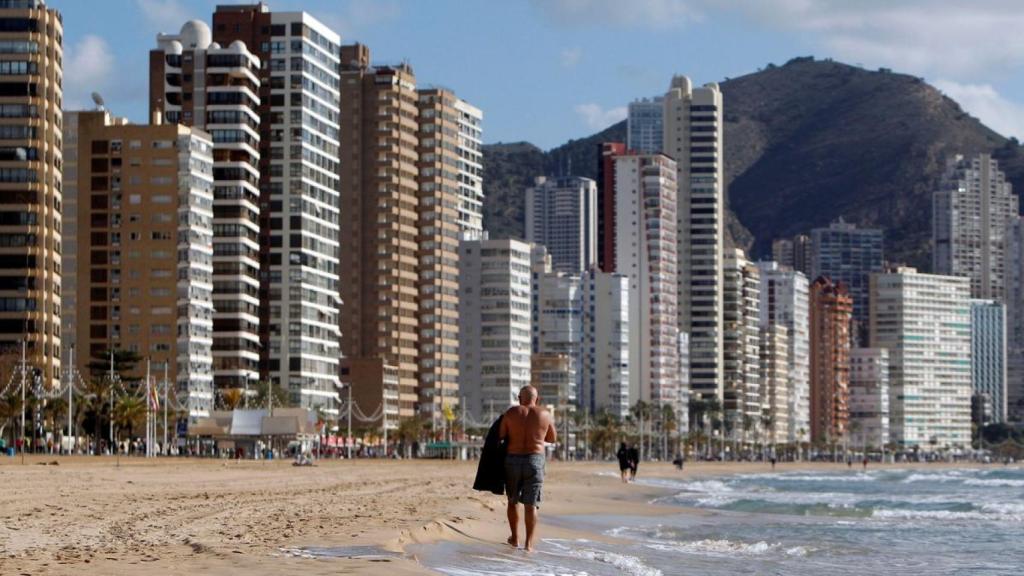 Un turista pasea por la playa de Benidorm, con su 'skyline' al fondo, hace unos meses.