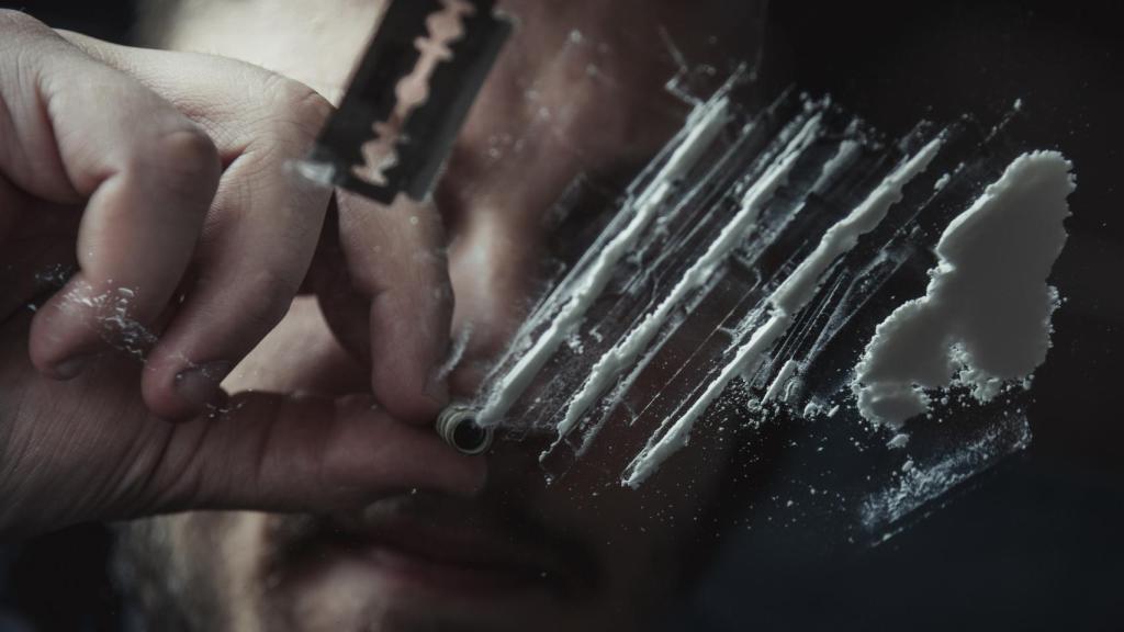 Un chico esnifa una raya de cocaína.