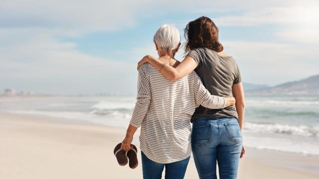 Una madre y una hija paseando por la playa.