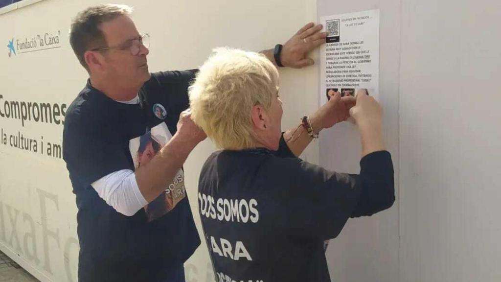 Damián y Felisa, los padres de Sara, pegando carteles en Valencia con códigos QR para recabar firmas en favor de una proposición no de ley que regule las operaciones de estética.