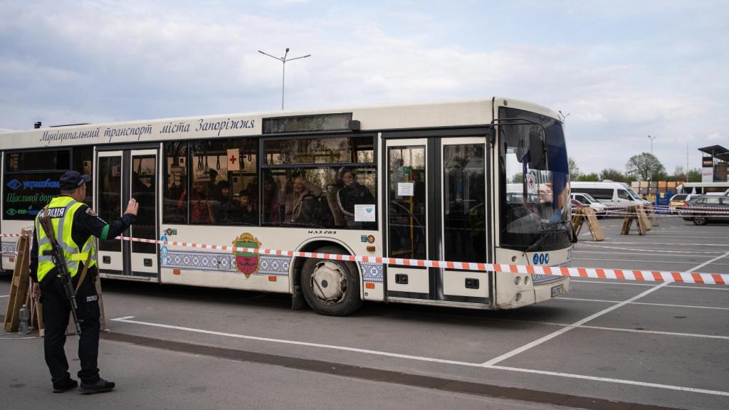 Un policía saluda al primer autobús llegado con refugiados de Azovstal.