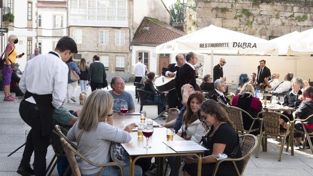 Un grupo de turistas consulta una carta en la terraza de un bar en Santiago de Compostela.