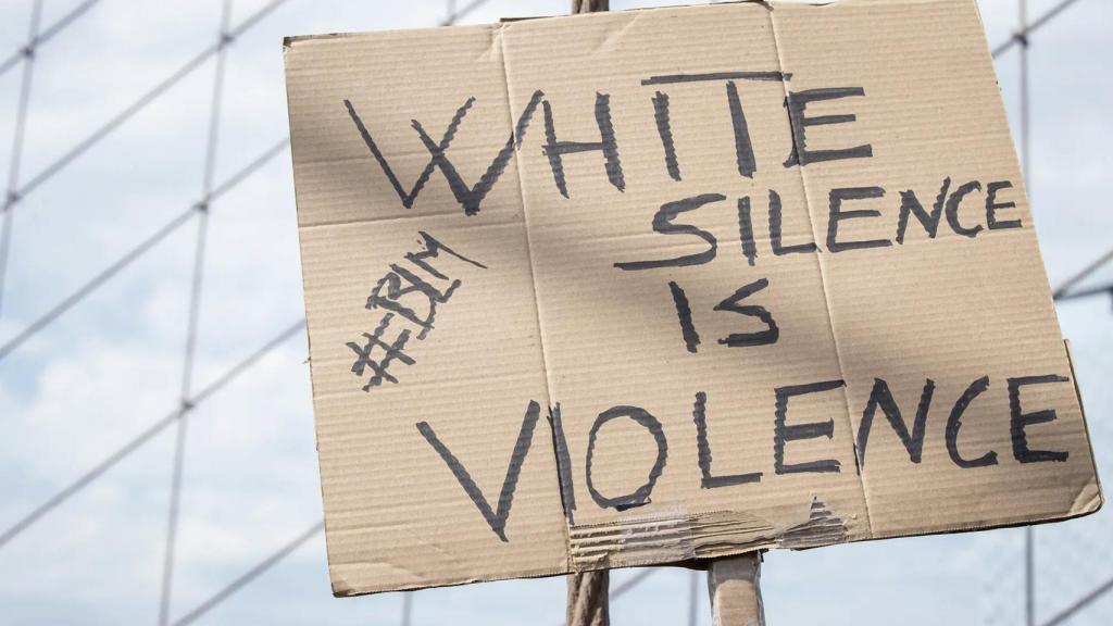 La pancarta de un activista de Black Lives Matter reza: El silencio blanco es violencia.
