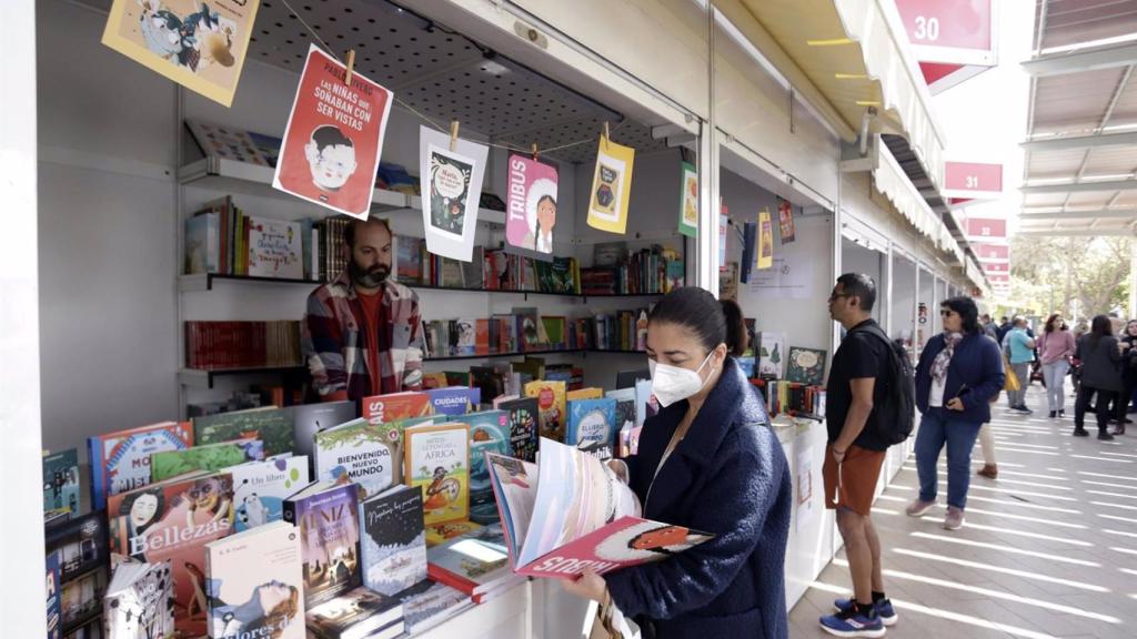 Una mujer consultando un libro en la Feria, en la Plaza de la Marina.