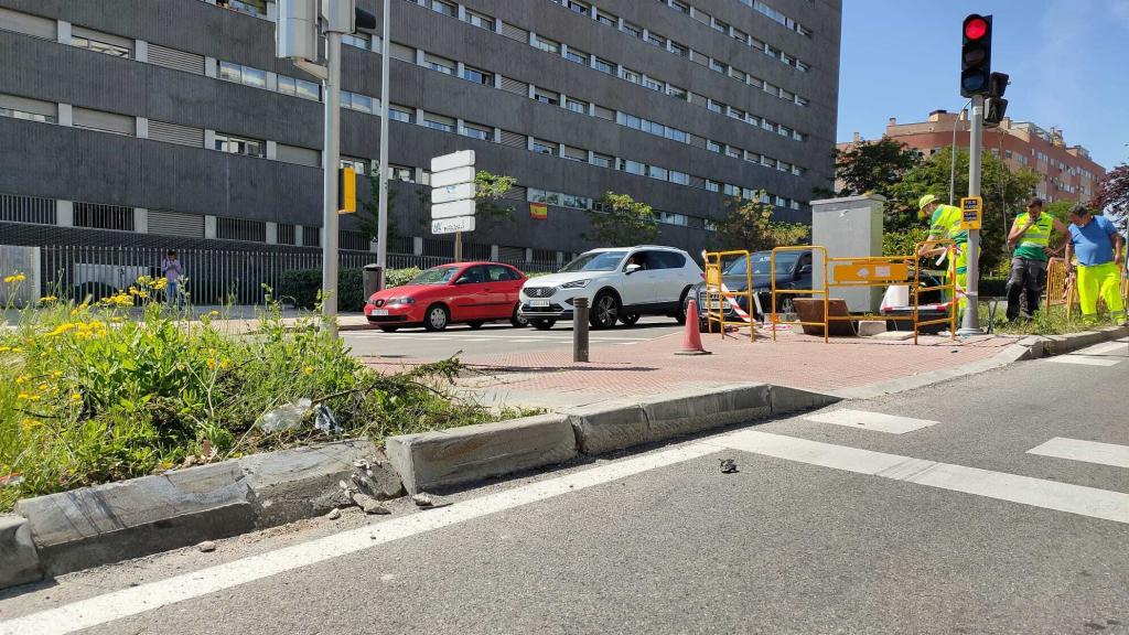 El bordillo levantado tras el siniestro y los operarios trabajando.