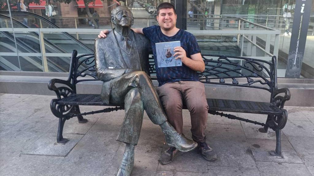 El periodista David Rubio junto a la escultura de Gastón Castelló en la plaza del 25 de mayo en Alicante.