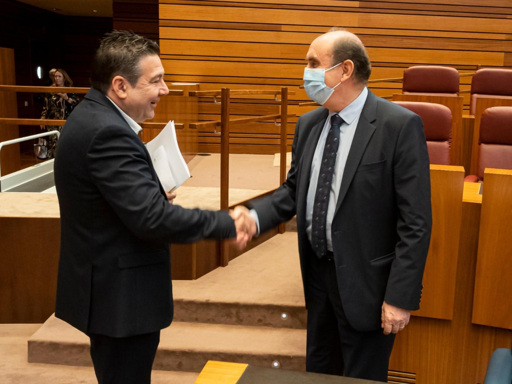 El portavoz del Grupo UPL-Soria Ya, Luis Mariano Santos, saluda al Procurador del Común, Tomás Quintana, este miércoles en las Cortes.