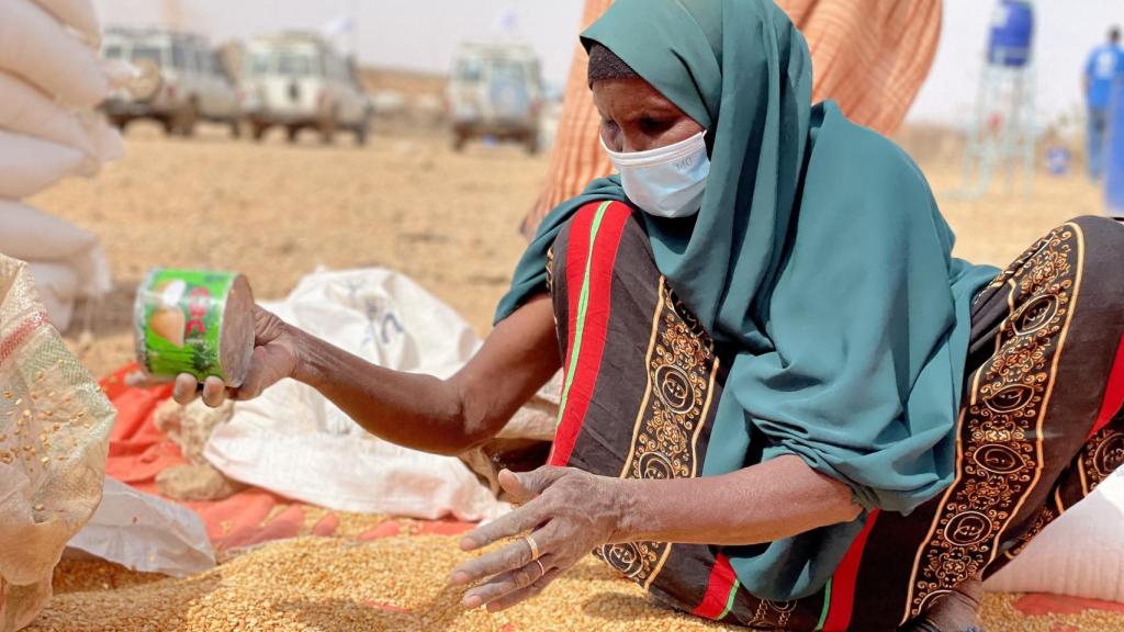 Una mujer recolecta grano en un campo de refugiados en Etiopía.