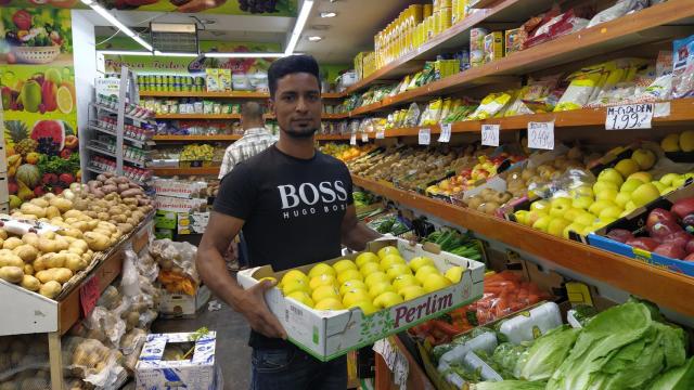 Mithu Sheik, frutero de Bangladés, muestra sus productos en su frutería del barrio de Quintana (Madrid).