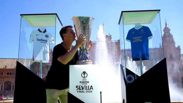 Un aficionado besa el trofeo de la Europa League entre las camisetas del Eintracht y el Rangers.