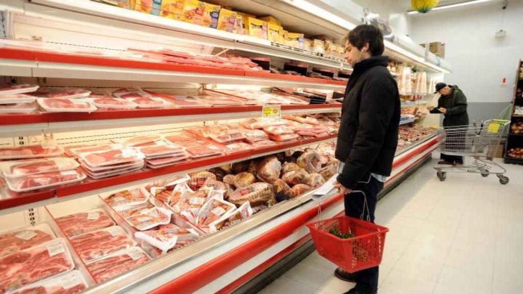 Un hombre comprando carne en un supermercado.