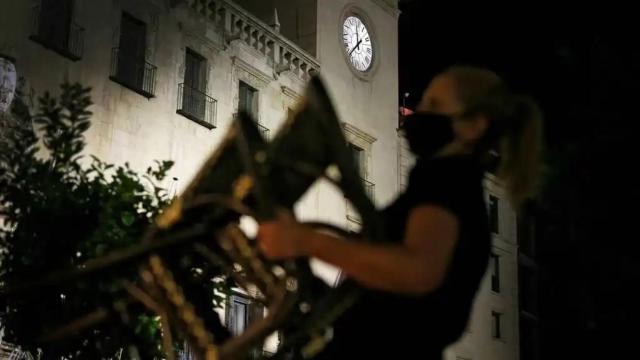 Una mujer recoge unas mesas ante la cercanía del toque de queda, en imagen de archivo.