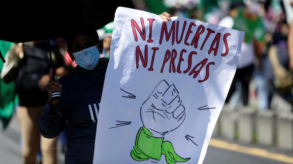 Un hombre en una manifestación por el aborto con una pancarta que reza: Ni muertas ni presas.
