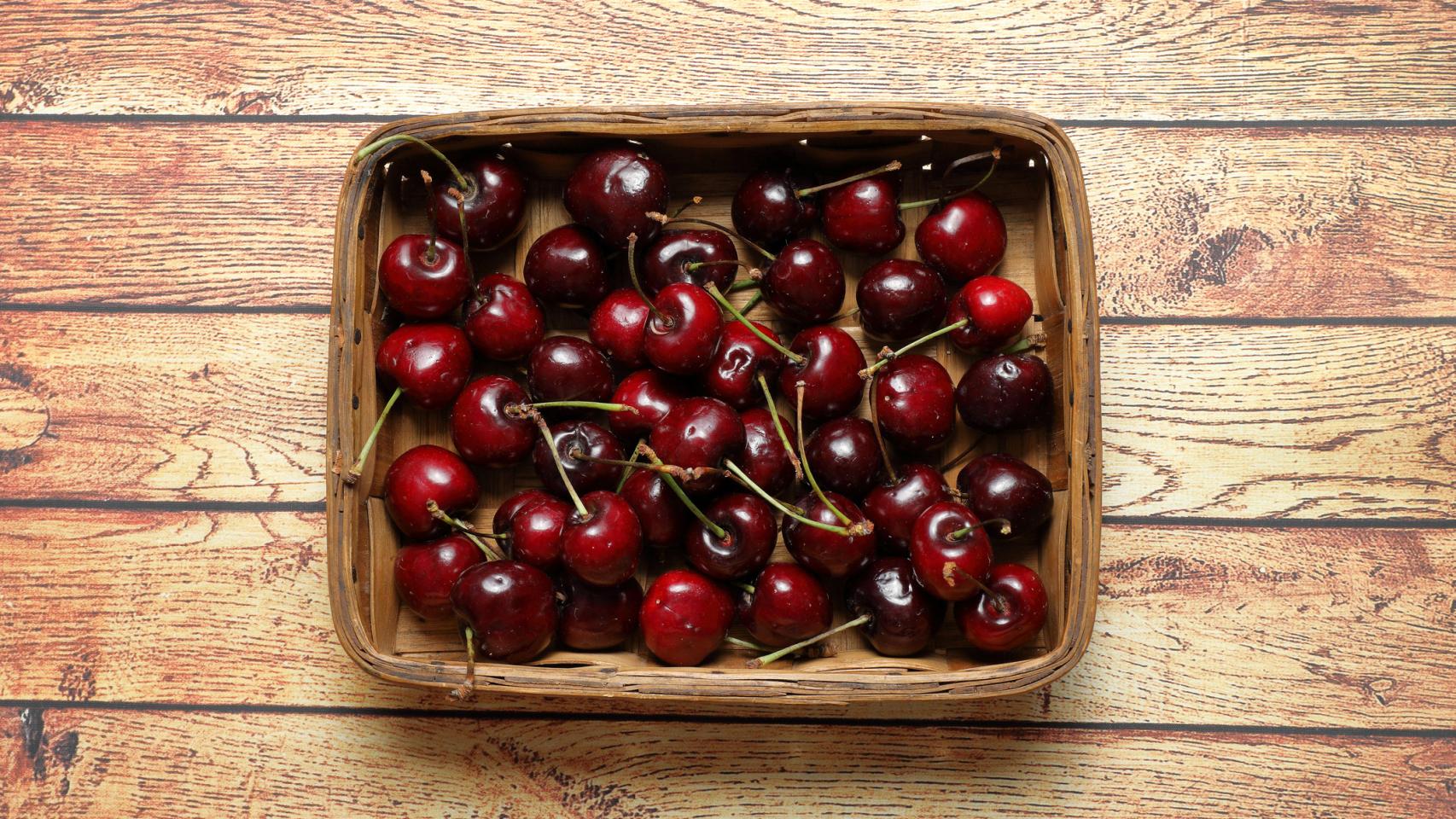 Una caja con cerezas de color oscuro.