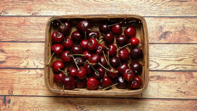 Una caja con cerezas de color oscuro.