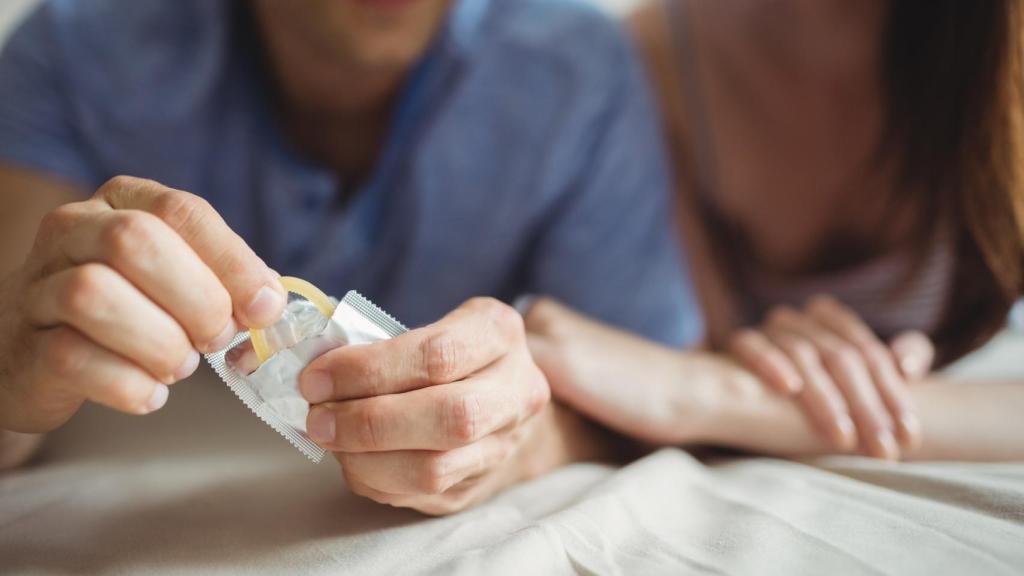 Primer plano de la pareja con un condón en la cama.