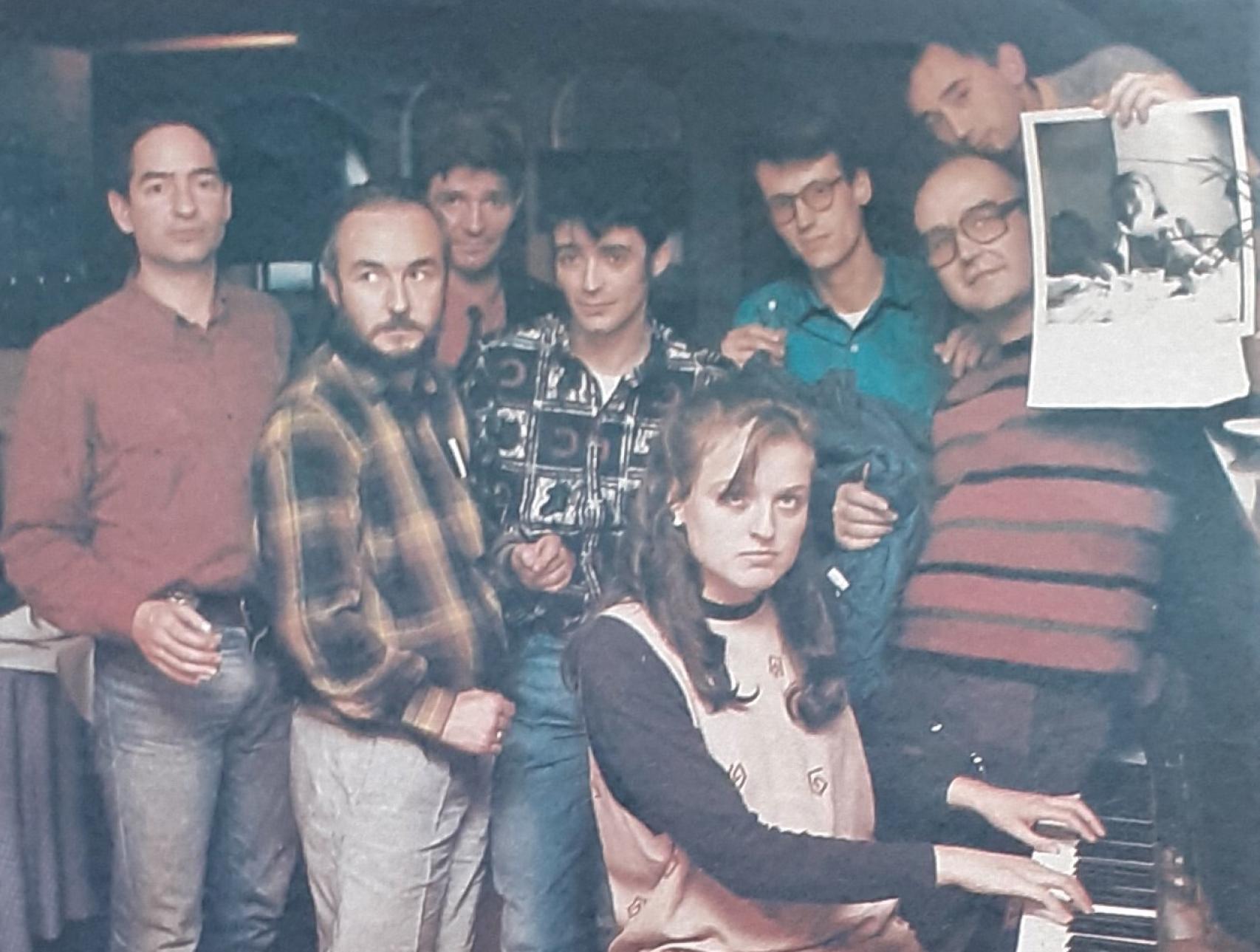 De izquierda a derecha, Javier Timermans , Luis Pérez-Mínguez, Jorge Berlanga, Alberto García Alix, Bárbara al piano, Juna Ramón  Yuste, Pablo Pérez-Mínguez y José Tono Martínez, sosteniendo la foto de Luis Izquierdo-Mosso (1986)