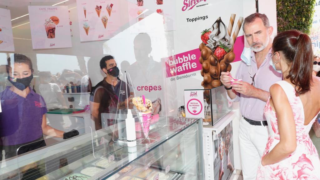 Felipe VI prueba el helado de turrón artesanal mientras la Reina habla con los dueños del establecimiento en Benidorm.