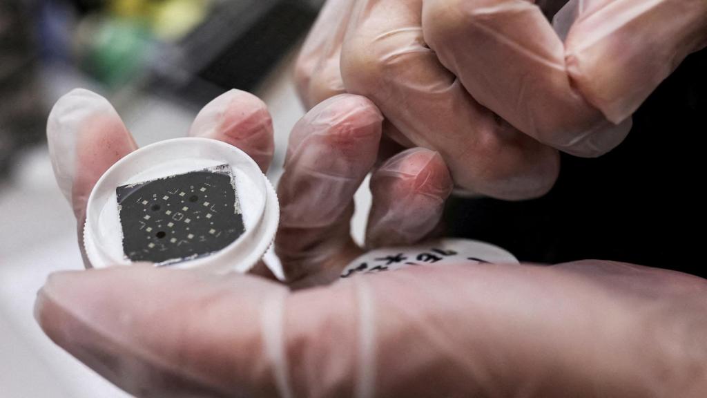 Un ingeniero sosteniendo un microchip en sus manos.