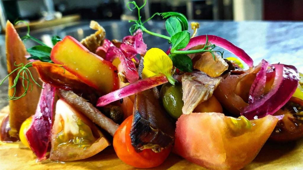 La ensalada de variedades de tomate y salazones como entrante del menú.