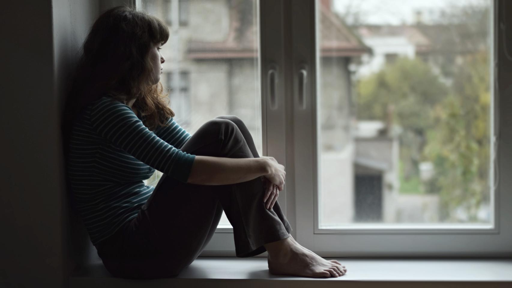 Un mujer joven sentada en la ventana.