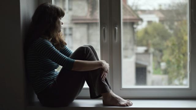 Un mujer joven sentada en la ventana.
