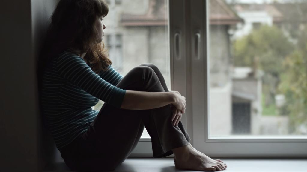 Un mujer joven sentada en la ventana.